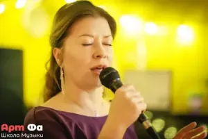 Крупный план: ученица поёт с закрытыми глазами на тёплом жёлтом фоне – Вокальный мастер-класс Максимова Даниила, март 2026